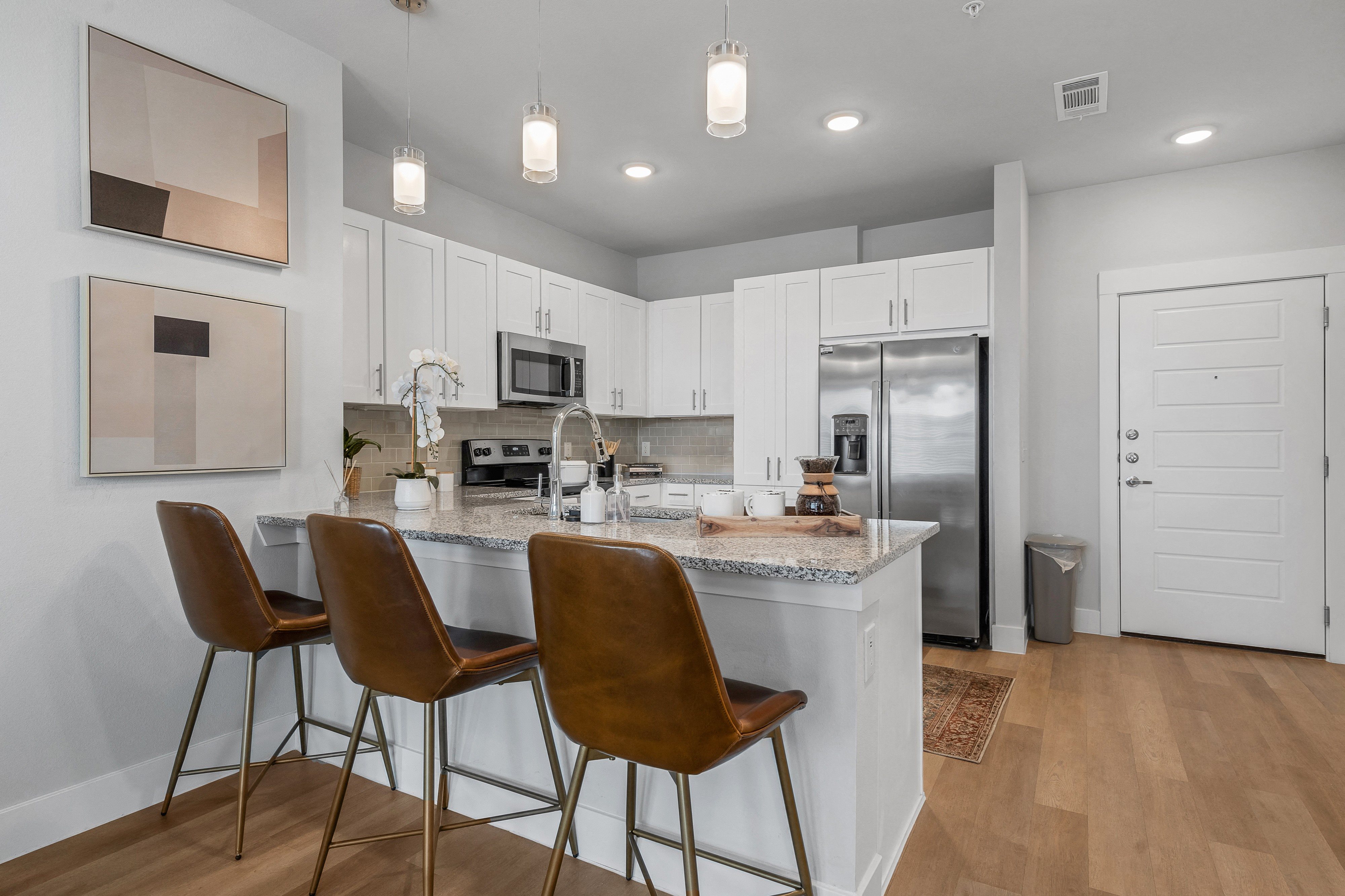 a kitchen with stainless steel appliances, granite countertops, and countertop seating at a senior apartment community